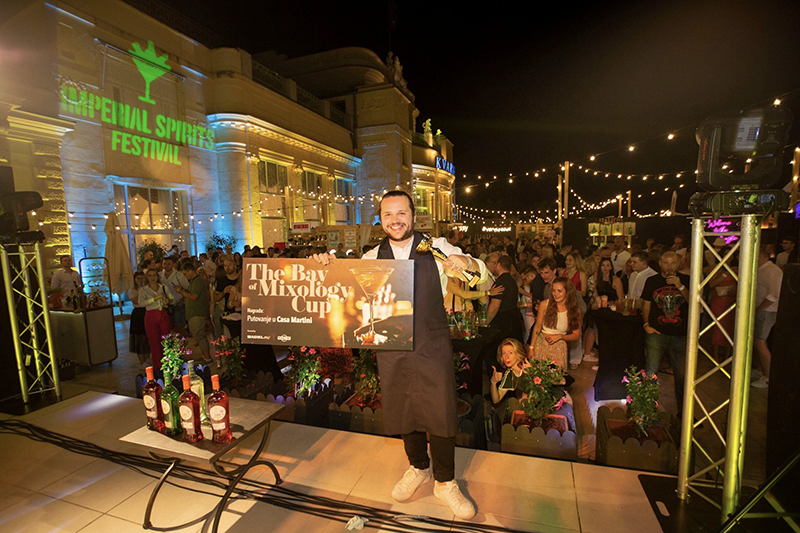 Foto eines Barkeepers, der triumphierend den The Bay of Mixology Cup hält und seinen Sieg beim Imperial Spirits Festival in Opatija, Kroatien, feiert.