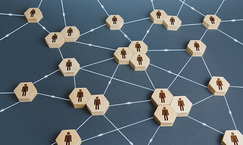 Grafik von miteinander verbundenen Holzsechsecken mit einer menschlichen Silhouette, die Vernetzung und menschliche Verbindungen in einem Unternehmens- oder sozialen Umfeld darstellt.