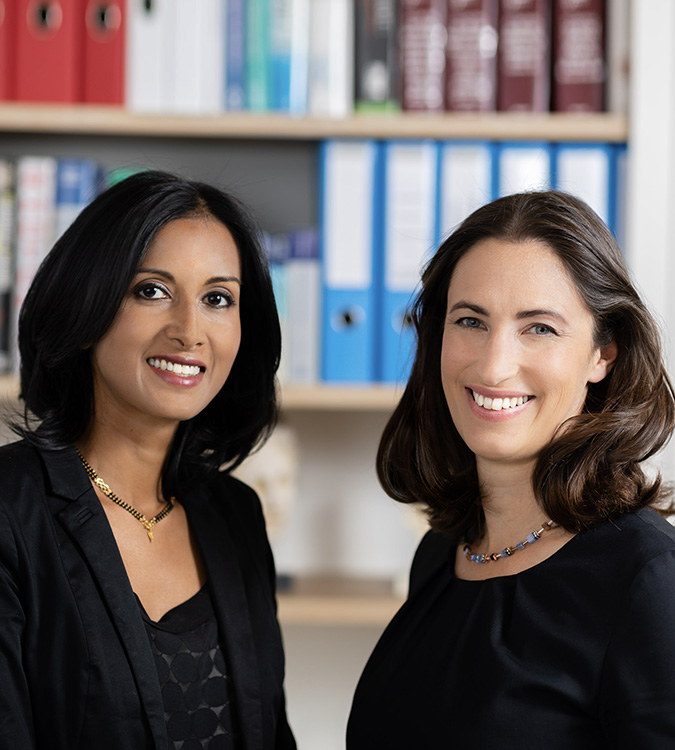 Foto von Dr. Sindhu und Dr. Rienmüller, das ihr professionelles Aussehen und ihre Präsenz einfängt und ihre Expertise und Rollen im medizinischen Bereich repräsentiert.